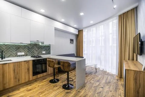 A kitchen with a counter and two stools, and a couch in the living room Stock Photos