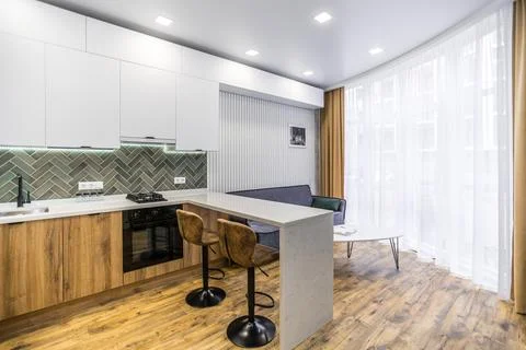 A kitchen with a counter and two stools, and a couch in the living room Stock Photos