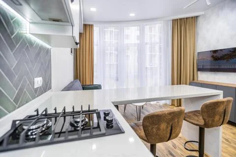 A kitchen with a counter and two stools, and a couch in the living room Stock Photos