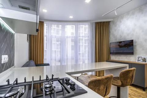 A kitchen with a counter and two stools, and a couch in the living room Stock Photos