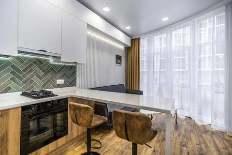 A kitchen with a counter and two stools, and a couch in the living room Stock Photos