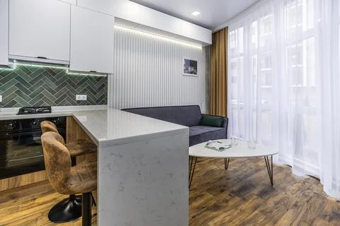 A kitchen with a counter and two stools, and a couch in the living room Foto stock
