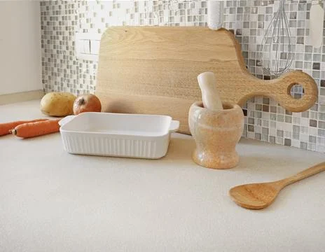 Kitchen counter with white baking dish stone mortar and wooden cutting board. Photos
