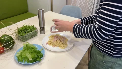 In the kitchen, a cute guy is blending ingredients to craft a perfect carbonara Stock Footage 302929198