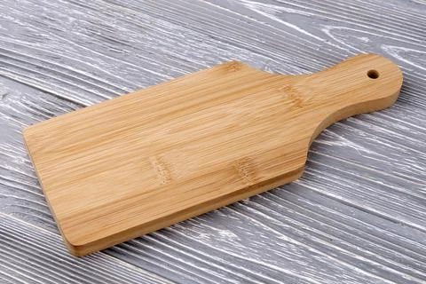 A kitchen cutting board lies on a gray table. Stock Photos