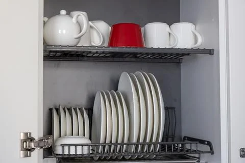 A kitchen dish rack stores an assortment of white ceramic plates and bowls on Foto stock