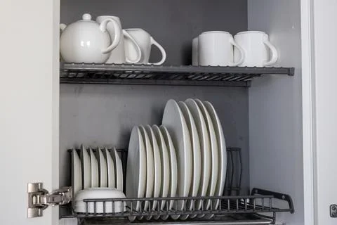 A kitchen dish rack stores an assortment of white ceramic plates and bowls on Foto stock