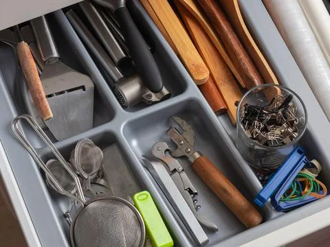 A kitchen drawer with a gray plastic insert organizes stainless steel, wood.. 스톡 사진