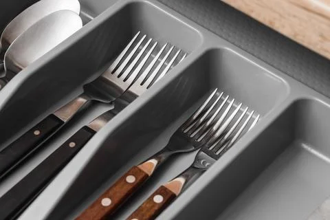 Kitchen drawer organizer with assorted silverware, forks, spoons, and knives  Stock Photos