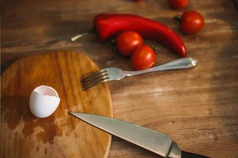 In the kitchen, eggshells, knife, fork and vegetables Stock Photos
