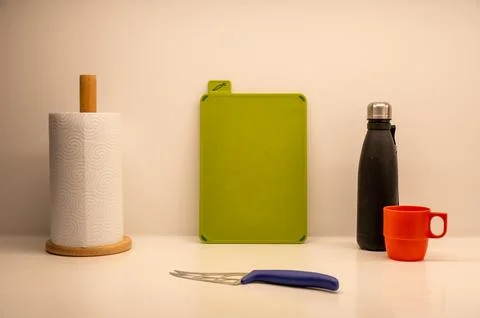 Kitchen essentials arranged neatly with a red mug, cutting board, and knife. Stock Photos