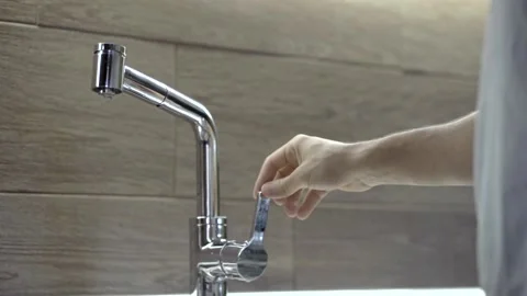 Kitchen faucet leaking with copy space to the right, a hand appears and turns Video stock 219399678