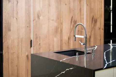 Kitchen faucet, modern kitchen in loft style, black marble table, wooden luxu Stock Photos