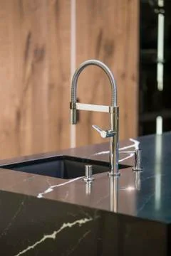 Kitchen faucet, modern kitchen in loft style, black marble table, wooden luxu Stock Photos