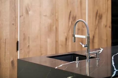 Kitchen faucet, modern kitchen in loft style, black marble table, wooden luxu Stock Photos