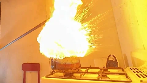Kitchen fire safety hazard, burning oil pot on stove on fire with a huge water Stock Footage 337713030