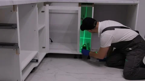 Kitchen fitter with an electronic level. Laser level when installing furniture 库存影片 234816905