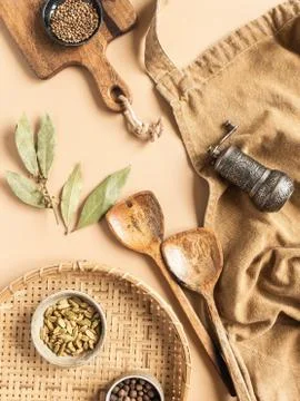 Kitchen flat lay of beige apron, small bowls with spices, metal spice mill, w Stock Photos