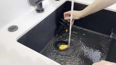 Kitchen garbage disposal process. Hand cleaning orange fruit leftovers in s.. Stock Footage 320185269