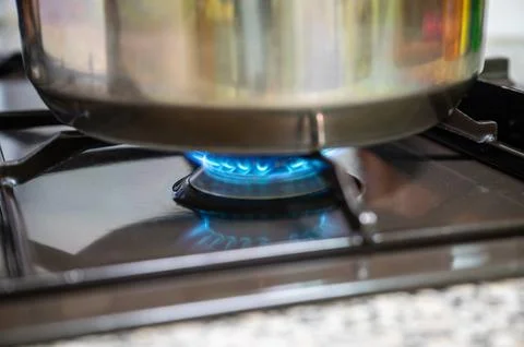 The kitchen gas is on, heating a pot. Stock-Fotos