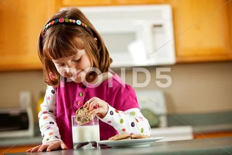 Kitchen girl: dunking a cookie into glass of milk Stock Photos