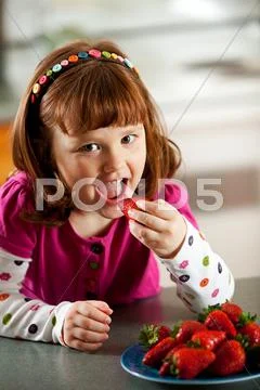 Kitchen girl: girl eating strawberries Stock Photos