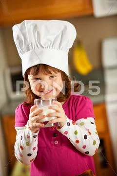 Kitchen girl: kid chef drinking milk Stock Photos