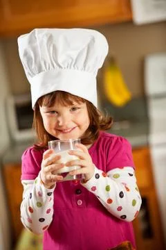 Kitchen girl: kid chef drinking milk Stock Photos