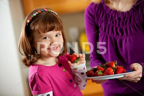 Kitchen girl: taking a berry from a plate Stock Photos