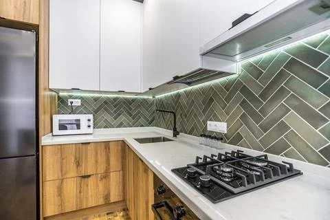 A kitchen with a green tile backsplash and a black stove 库存照片