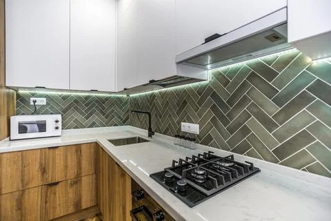 A kitchen with a green tile backsplash and a black stove 库存照片