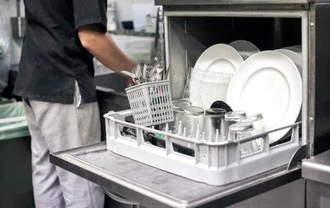 Kitchen hand with an open dishwasher Stock Photos