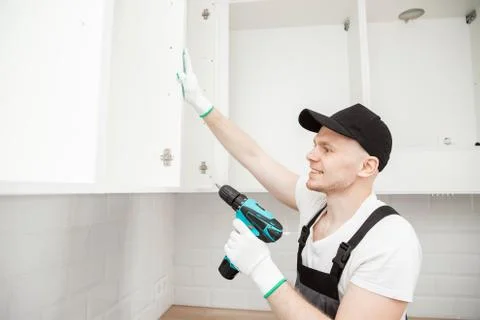Kitchen installation man. Worker assembling furniture cabinet hinge Stock-Fotos