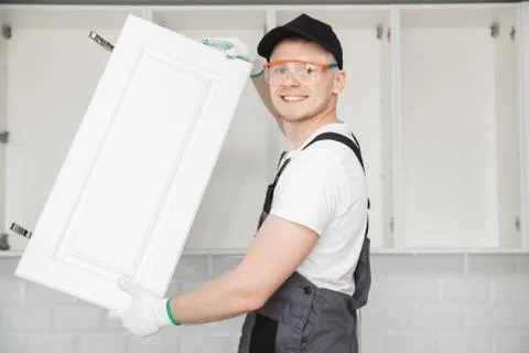 Kitchen installation, worker fixing door cabinet front assembling furniture Foto stock