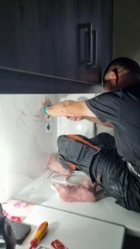 Kitchen installer fitting electrical outlet during cabinet installation Stock Photos