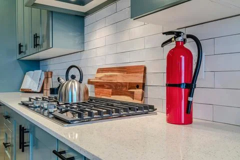 Kitchen interior with fire extinguisher and cooking unit on the white countertop Stock Photos