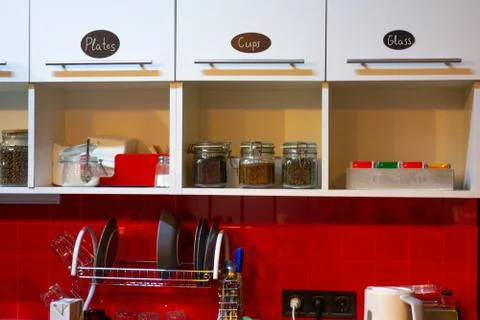 Kitchen interior at home or small office. Red tile wall and white shelf. Cabi Stock-Fotos