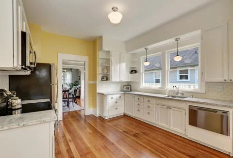 Kitchen interior with white cabinets, stainless steel appliances, yellow wall Stock Photos