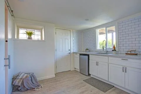 Kitchen interior with white cabinets, tiled wall and hardwood floor. Stock Photos