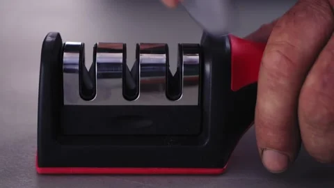 A kitchen knife and a person's hand is sharpened in a special sharpener for kniv Stock Footage 281783017