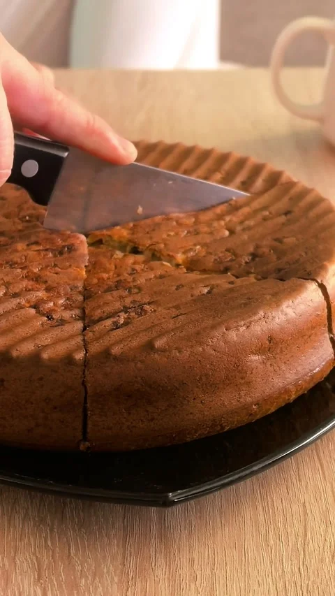 Kitchen knife cuts a rustic homemade cake into portions on a table, home Stock Footage 339848770