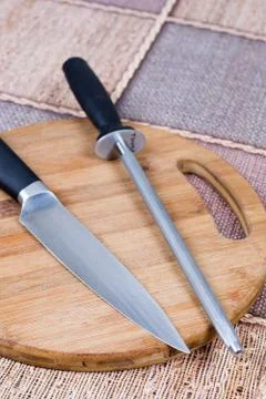 Kitchen knife with knife sharpener tool on the kitchen wooden board Stock Photos