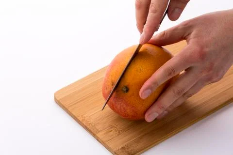 Kitchen knife sinking into mango for a first cut Stock Photos