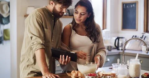 Kitchen, learning or couple on tablet for baking recipe method, lunch or guide Stockfoto's