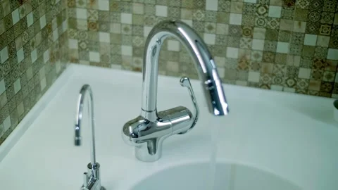In kitchen, a man turns on the water on chrome modern faucet, then turns it off Stock Footage 297789082