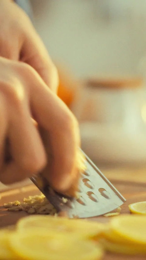 In kitchen a mans hands expertly grate fresh ginger on a metal grater releas Stock Footage 334395042