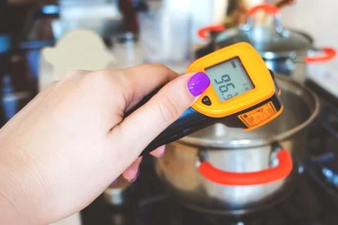 Kitchen measuring infrared thermometer. Pyrometer in a hand when cooking Stock Photos
