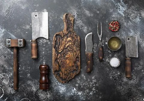 Kitchen meat utensils set on dark kitchen background. Meat cleaver,fork,knife Stock Photos