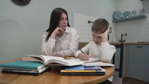 Kitchen, mother and son, sitting together at the table, do homework Stock Footage 257588843
