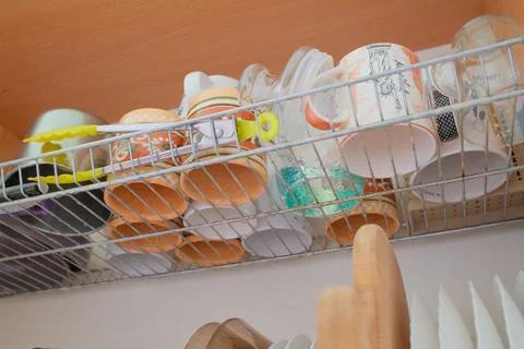 Kitchen mugs and cups drying on metal rack in cabinet Stock Photos